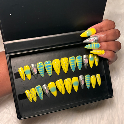 Vibrant yellow press-on nails featuring blue aura airbrush, silver chrome accents, abstract line art, and isolated chrome, blooming gel Designed on 100% Gel X tips for a salon-quality, reusable finish. Available in Square, Stiletto, Ballerina, and Coffin shapes.