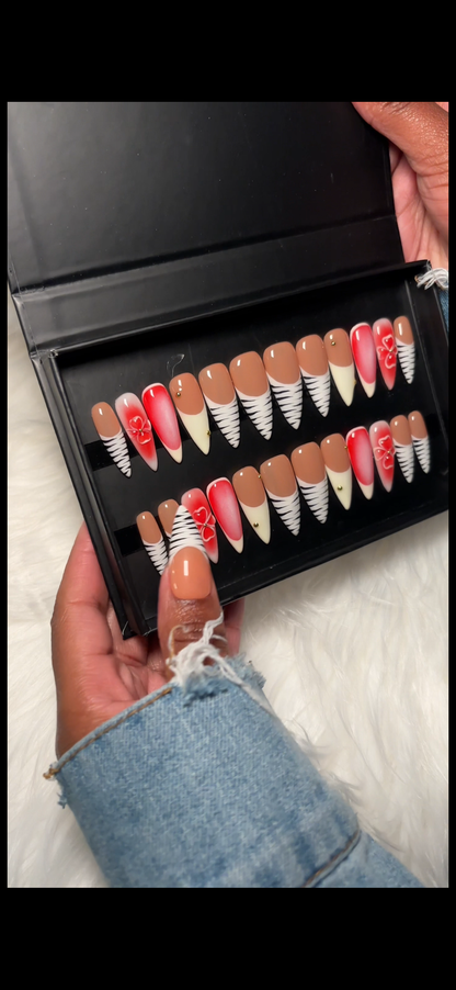 Multi-design press-on nails featuring zebra French tips, pink 3D floral accents, pink & white aura airbrush, and delicate gold charm details. Hand-painted on 100% Gel X tips for a salon-quality, reusable finish. Available in Square, Stiletto, Ballerina, and Coffin shapes.